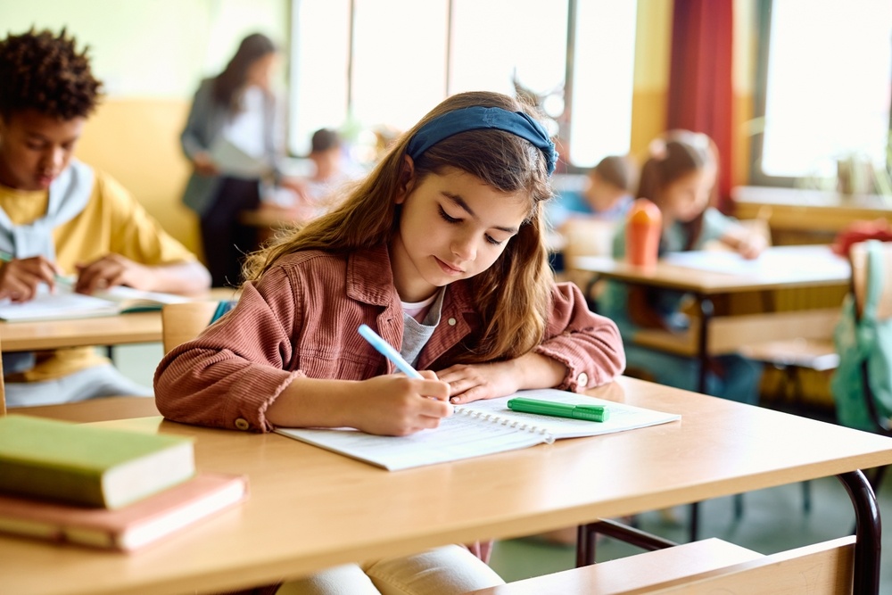 Young girl writing in her notebook during a private school education class