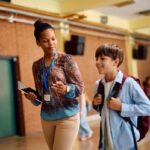 Teacher discussing private school curriculum with a student walking through school hallway