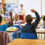 Diverse students eagerly raising hands in class showing how STEM for gifted children keeps advanced learners actively engaged and challenged