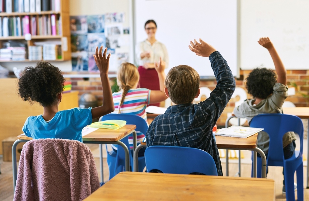 Diverse students eagerly raising hands in class showing how STEM for gifted children keeps advanced learners actively engaged and challenged