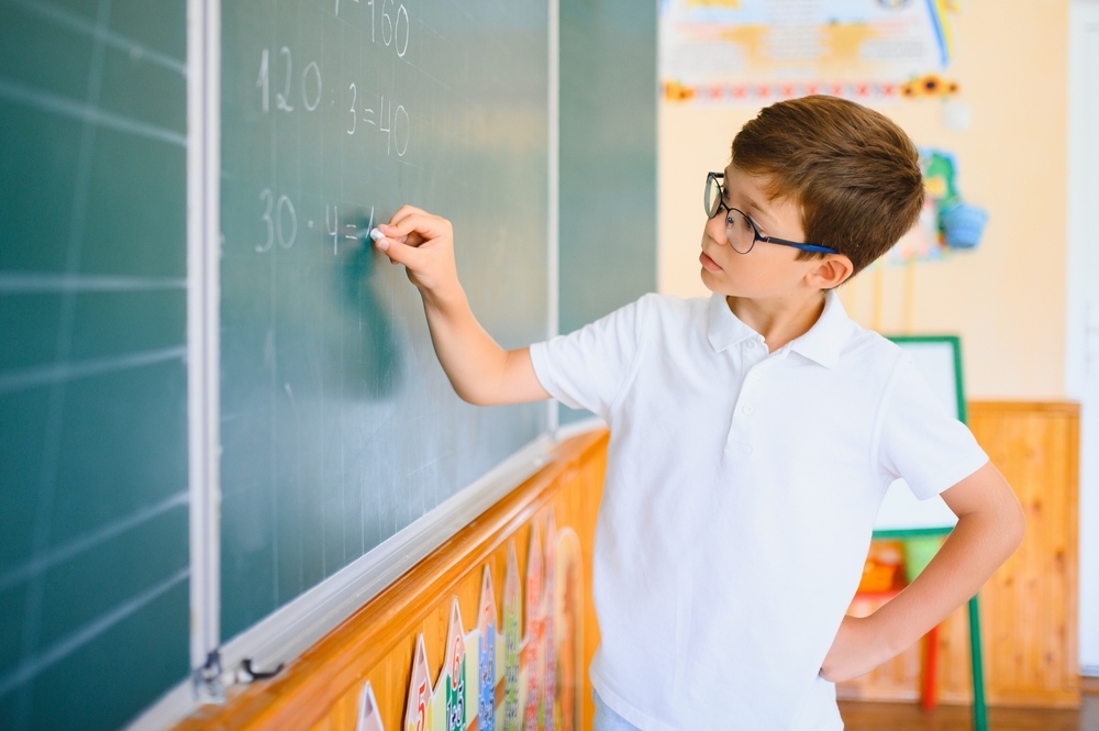 Focused student solving math equations on a chalkboard demonstrating how STEM teaches kids to solve problems through applied thinking