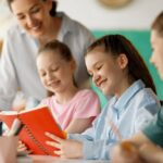 Teacher closely supporting two students reading together demonstrating how private school small class sizes enable individual attention and responsive instruction