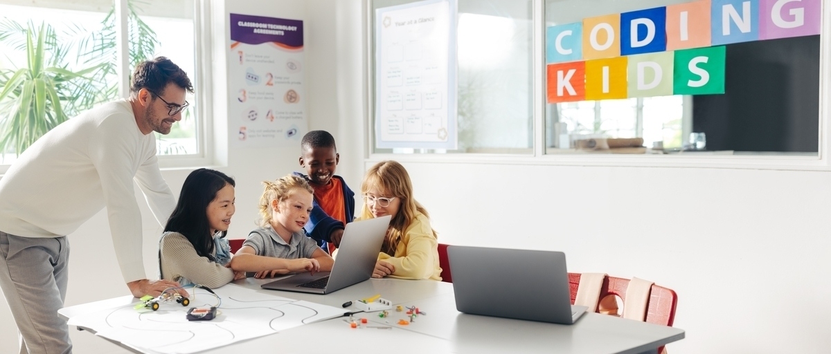 Children collaborating on coding for kids while a classmate explains her idea