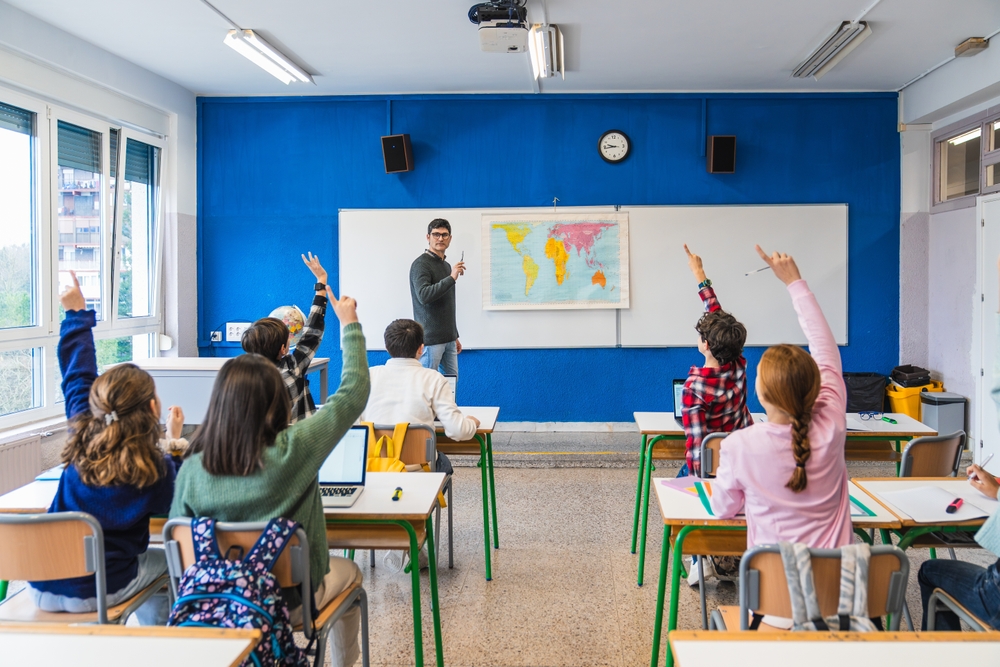 Students raising hands in an engaged classroom at a private school near Bensonhurst Brooklyn NY