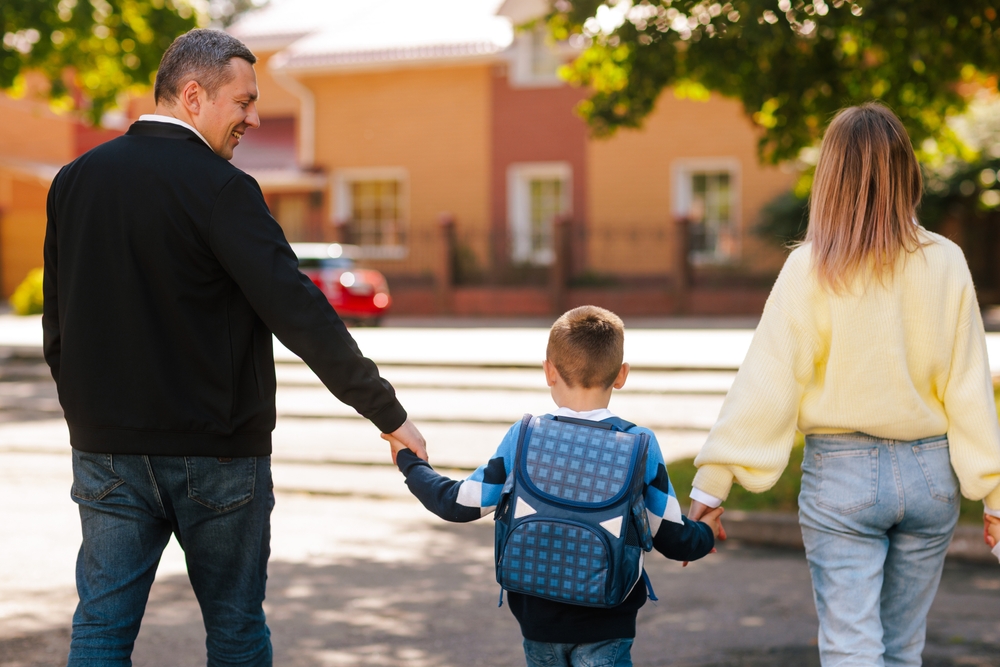 Two parents walking their child to school representing the active private school parent involvement that strengthens the home and school partnership