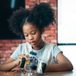 Young girl deeply focused on assembling a circuit robotics project illustrating how STEM and creativity develop together through hands-on open-ended design challenges