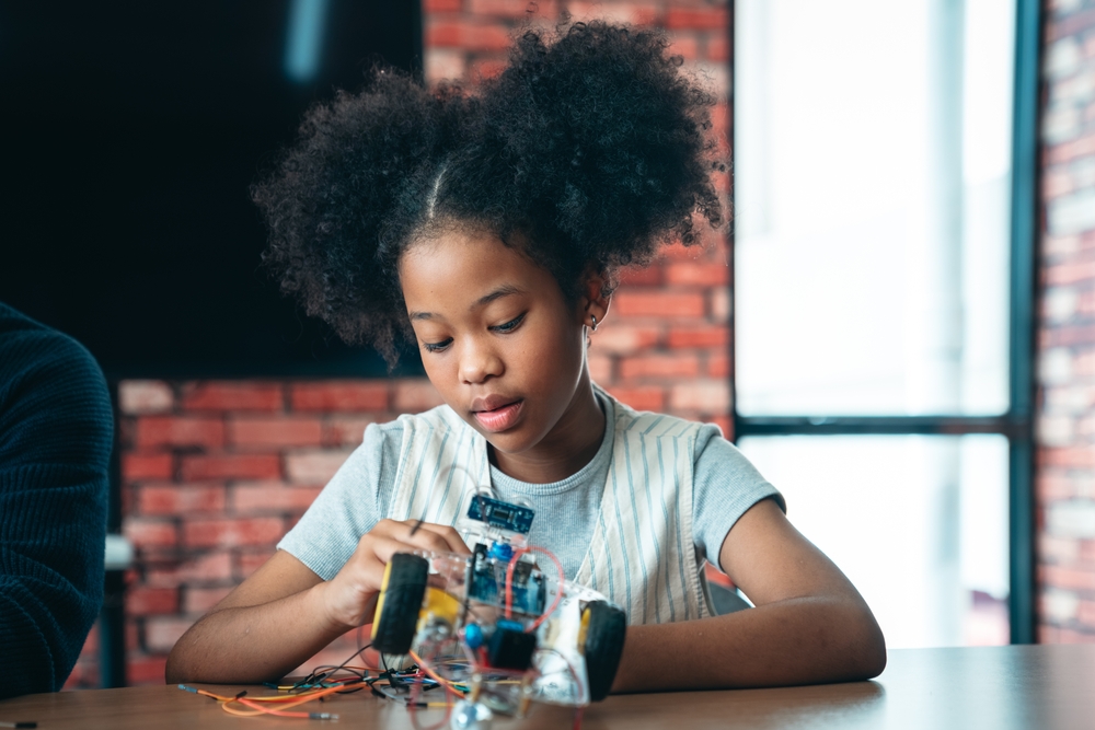 Young girl deeply focused on assembling a circuit robotics project illustrating how STEM and creativity develop together through hands-on open-ended design challenges