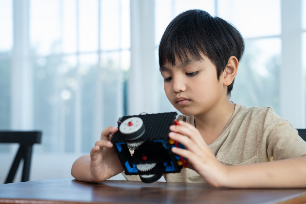 Focused student assembling a robotic vehicle independently before group collaboration demonstrating the individual contribution dimension of STEM and teamwork skills