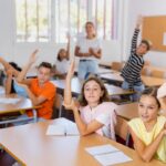 Upper elementary students eagerly raising their hands in class, demonstrating academic engagement, confidence, and the benefits of private school preparation for middle school success.