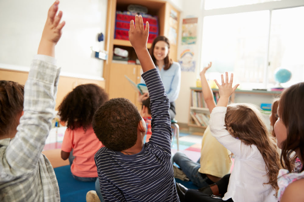 Young students raising hands eagerly in a classroom at a private school near Bay Ridge Brooklyn NY