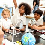 Diverse young students actively exploring science models and tools in a lab setting illustrating how STEM education and resilience develop together through hands-on investigative learning