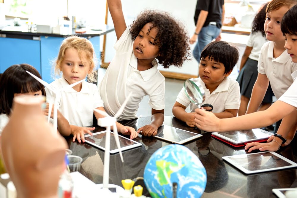 Diverse young students actively exploring science models and tools in a lab setting illustrating how STEM education and resilience develop together through hands-on investigative learning