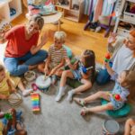 Young children and teachers playing instruments together in a circle showing the collaborative and cognitive benefits that private school arts and music programs provide from an early age