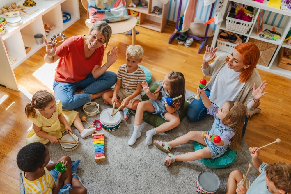 Young children and teachers playing instruments together in a circle showing the collaborative and cognitive benefits that private school arts and music programs provide from an early age