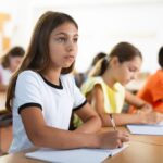 Focused student writing carefully in a notebook at her desk representing the attentive independent work habits that private school reading and writing development builds across the elementary years