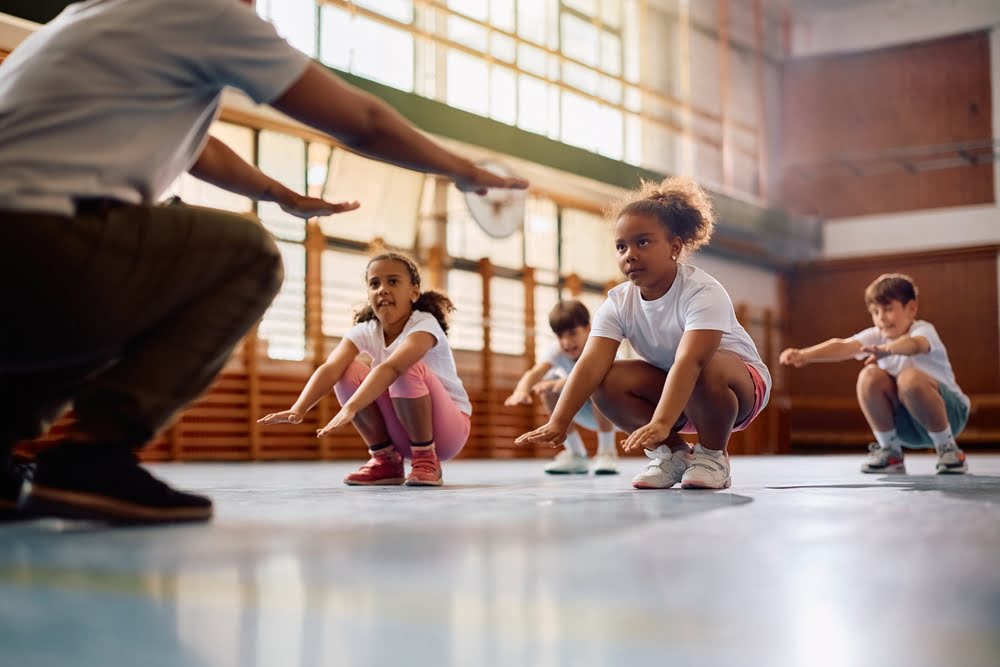 Young students focused and ready to move in a gym class illustrating how STEM and physical education work together to prepare the brain for learning and cognitive performance